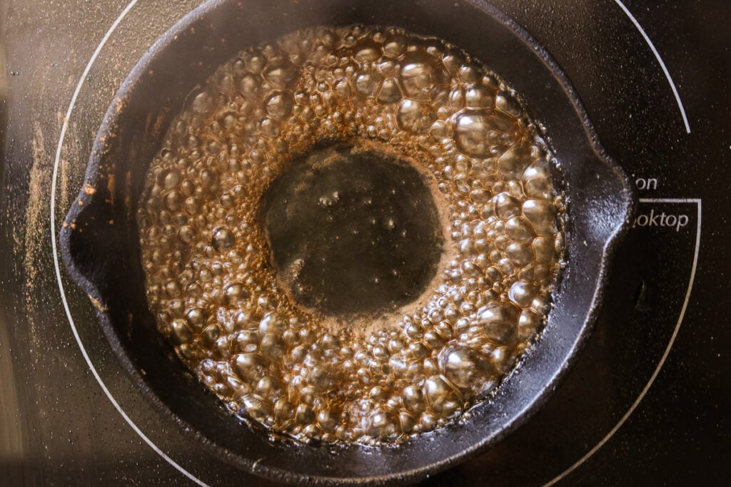 Sugar, water, cinnamon, and salt simmering in a small skillet