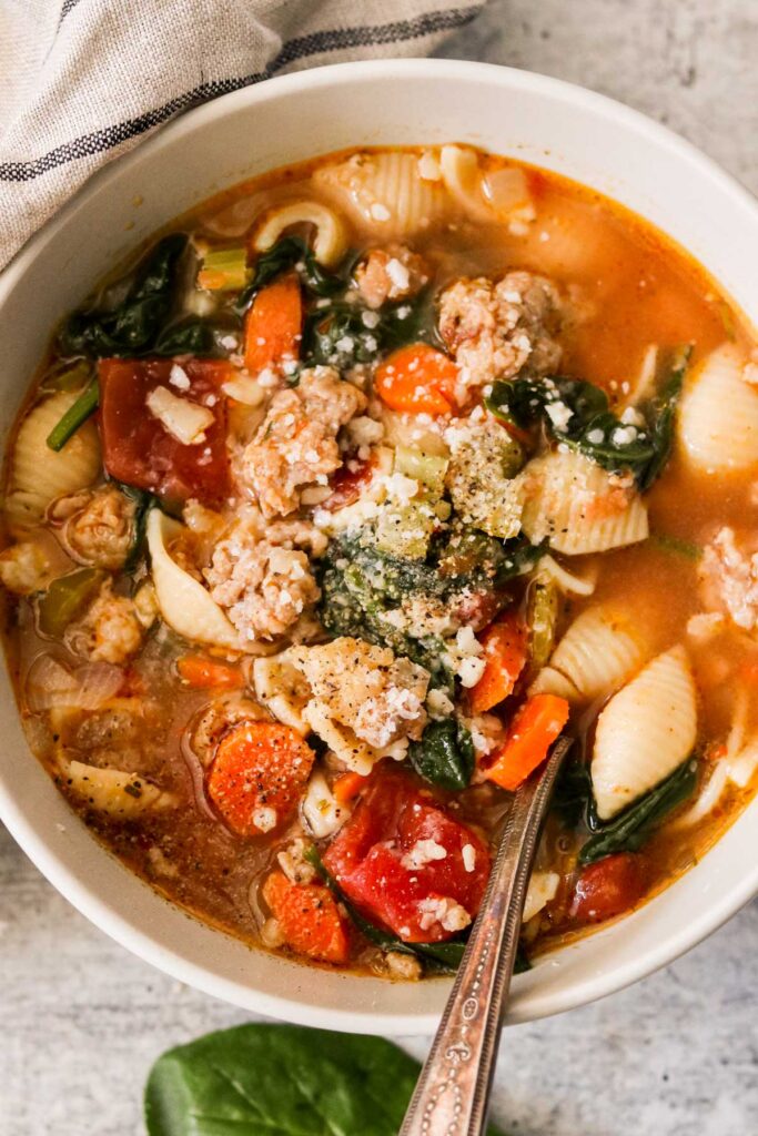close up of Italian sausage soup in a bowl with vegetables and shell pasta