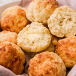 several biscuits in a basket with one sliced open to show the middle