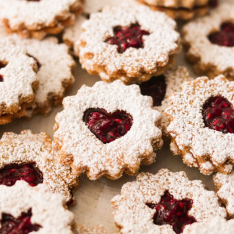 a close up of linzer cookies filled with raspberry jam and dusted with powdered sugar