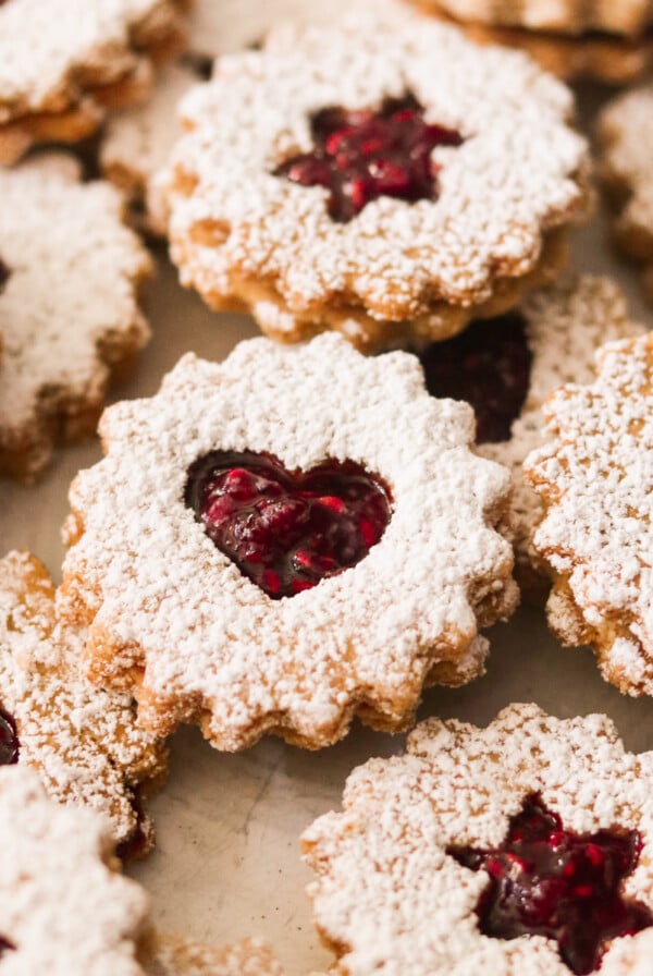 a close up of linzer cookies filled with raspberry jam and dusted with powdered sugar