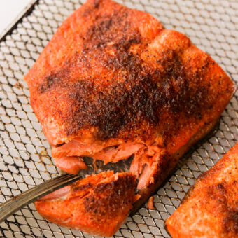 an air fried salmon fillet with a piece broken off to show the flaky middle.