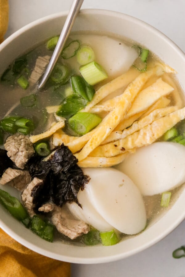 a white bowl filled with a Korean soup called tteokguk.