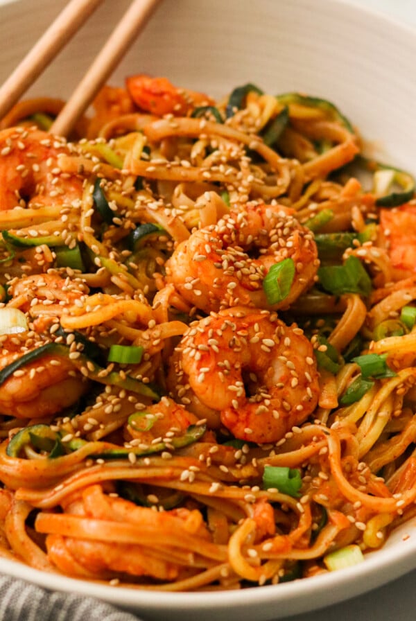 chopsticks resting on the side of a bowl of korean spicy noodles