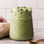 a glass jar filled with matcha chia pudding and topped with dalgona.