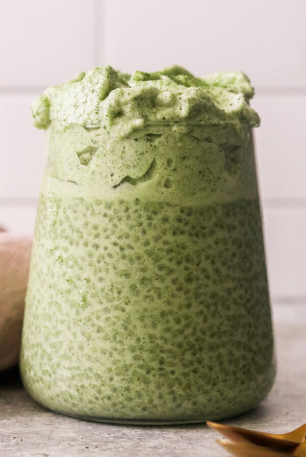 a glass jar filled with matcha chia pudding and topped with dalgona.