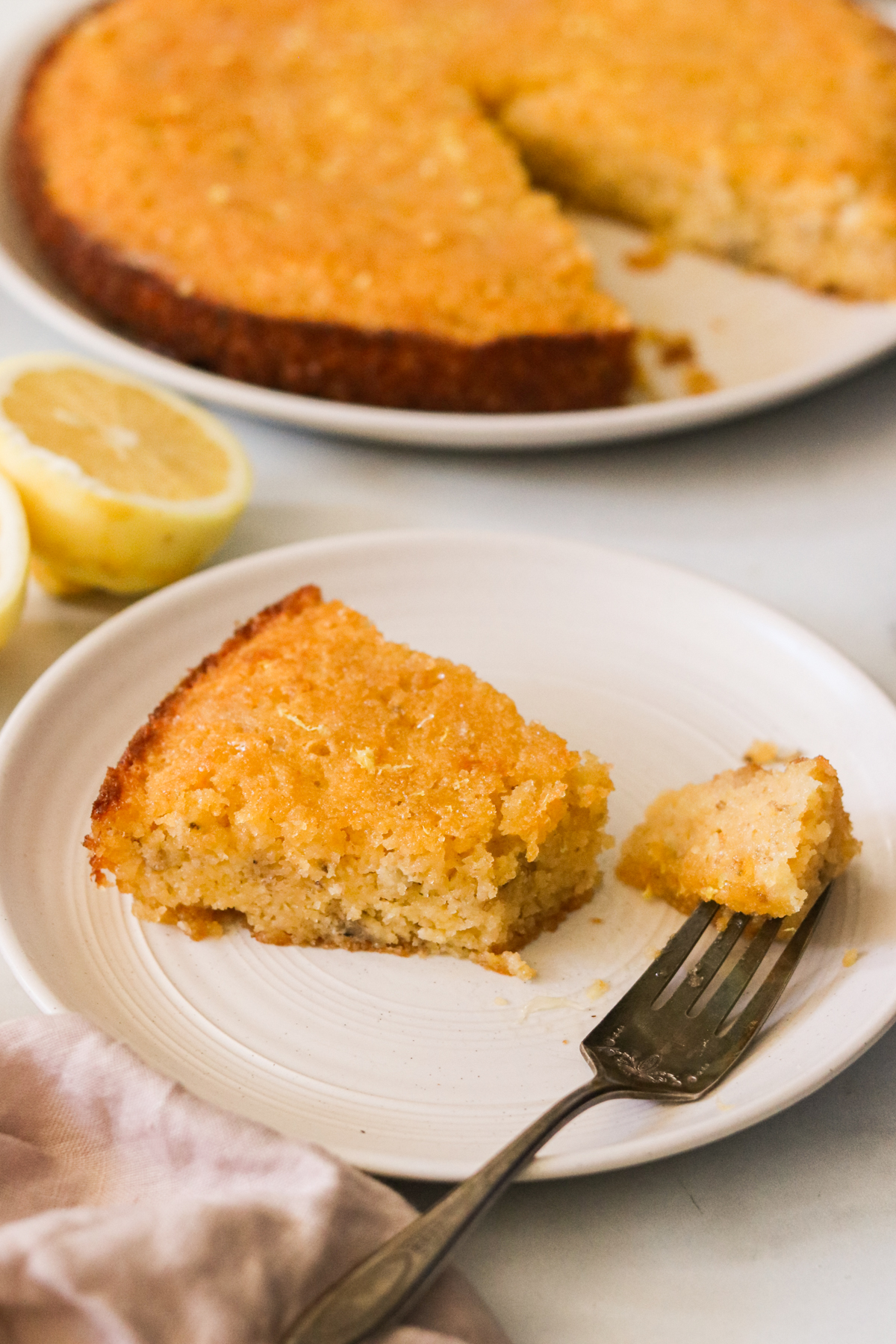 a slice of gluten-free lemon cake on a white plate with a bite cut off and resting on a fork 