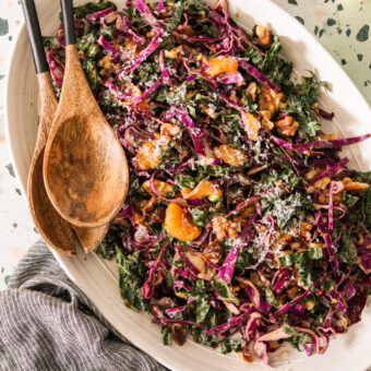 Purple cabbage slaw served on a platter, with kale, dates, walnuts, and Mandarin oranges