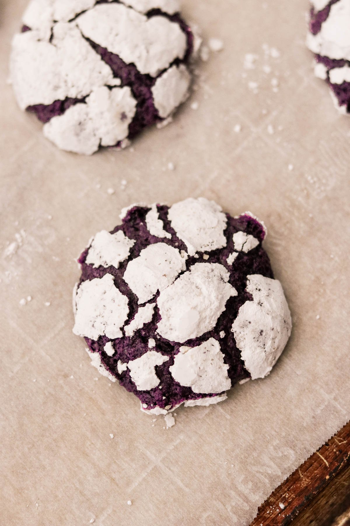 baked ube crinkle cookies on a sheet of parchment paper