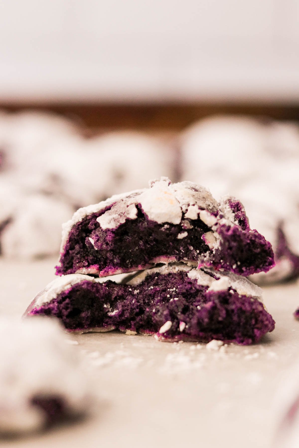 two ube crinkle cookies stacked on top of each other showing the vibrant purple center. 