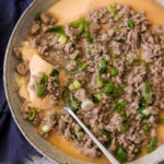 an overhead shot of a bowl filled with Chinese steamed egg and topped with minced pork and green onions.