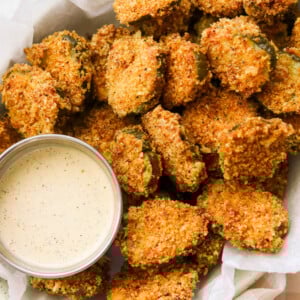 an up close photo of keto fried pickles on a platter next to a small bowl of ranch