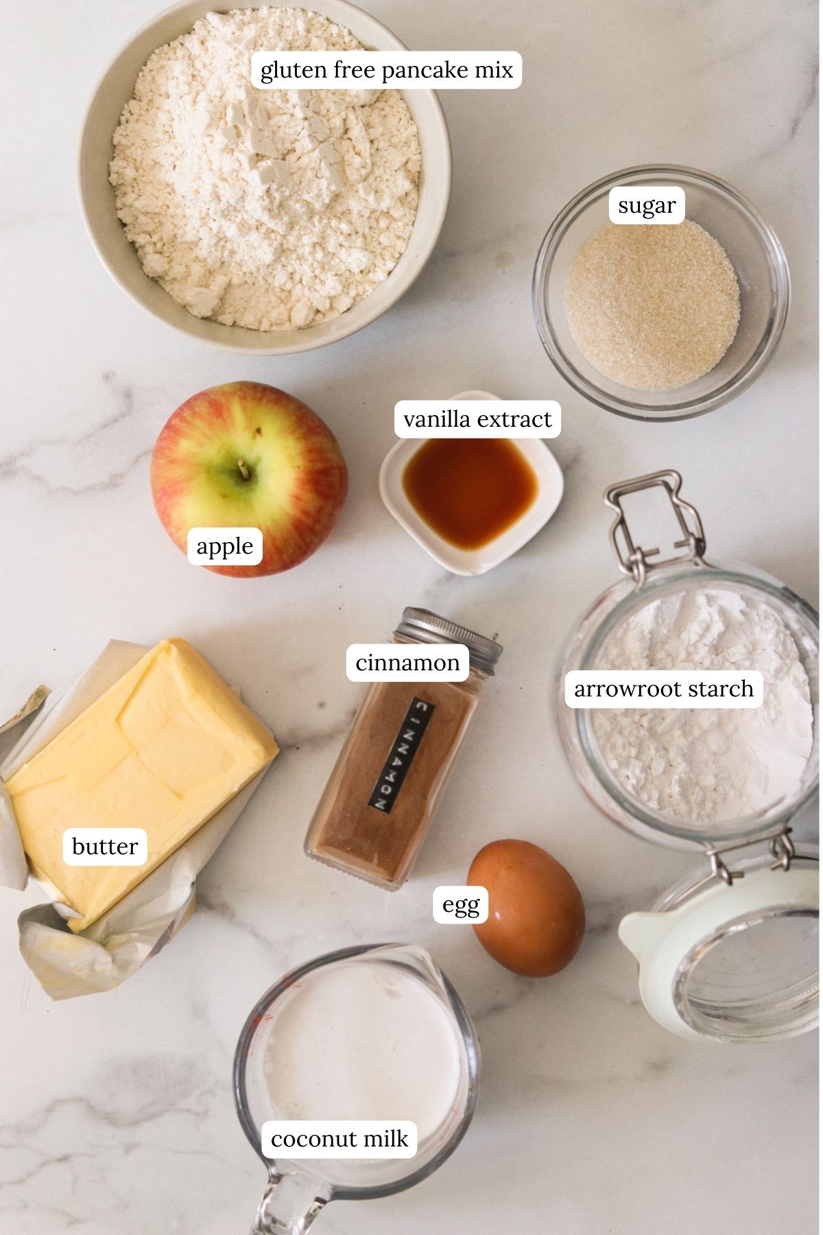 a photo of recipe ingredients: apple, vanilla extract, arrowroot starch, egg, butter, sugar, coconut milk, and pancake mix. 