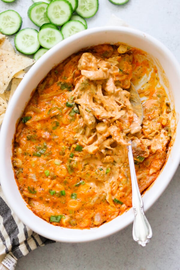 an overhead shot of buffalo chicken dip in a white baking dish with a spoon resting on the side