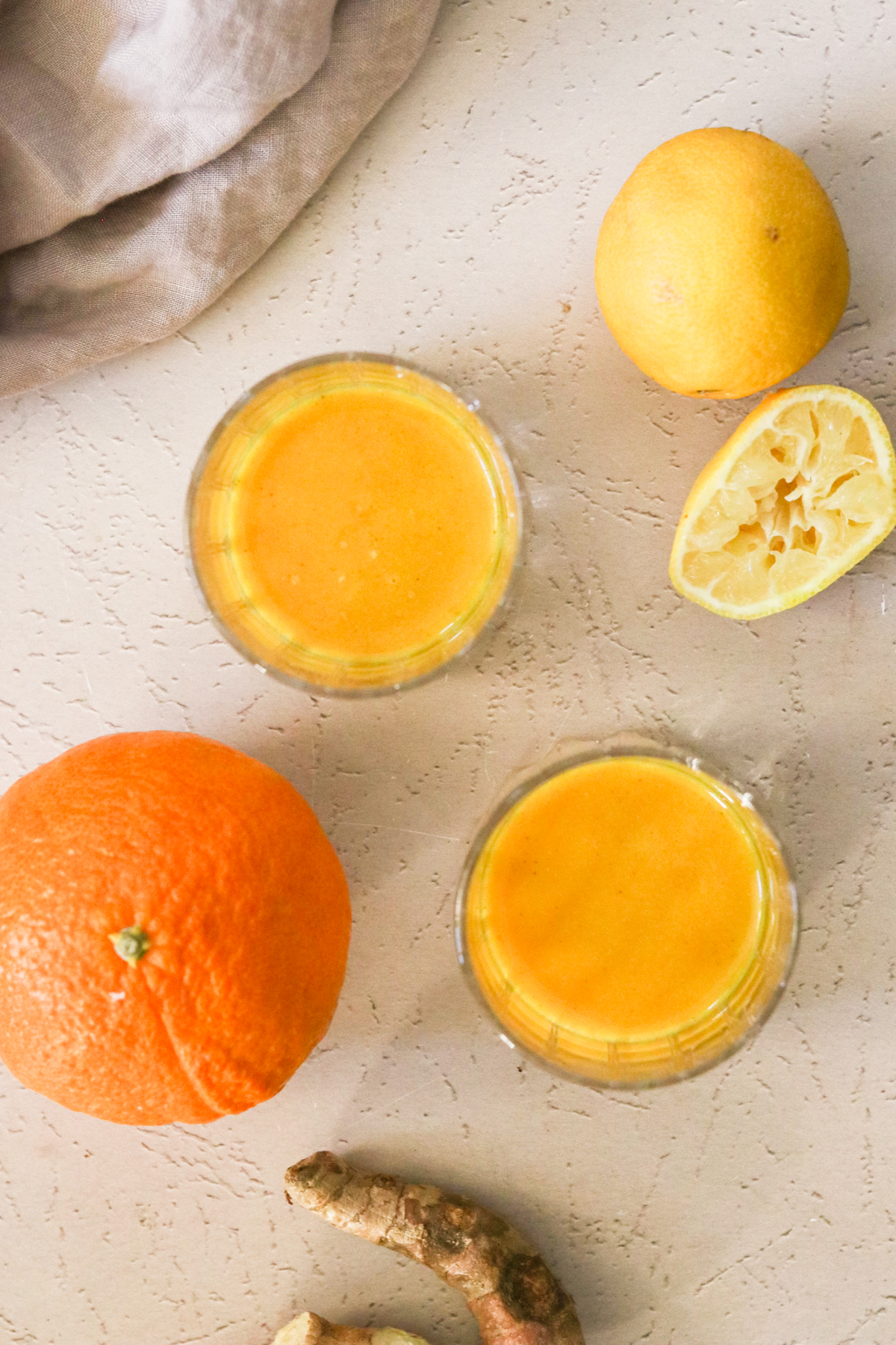an overhead shot of immunity shots in glasses next to fresh citrus fruit