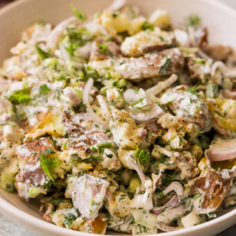 a close up photo of smashed potato salad in a large bowl