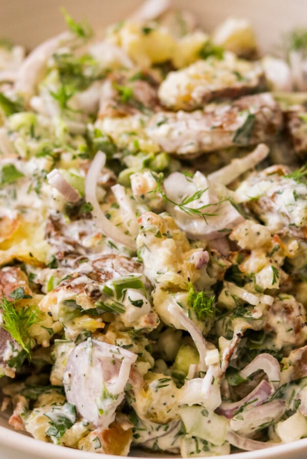 a close up photo of smashed potato salad in a large bowl