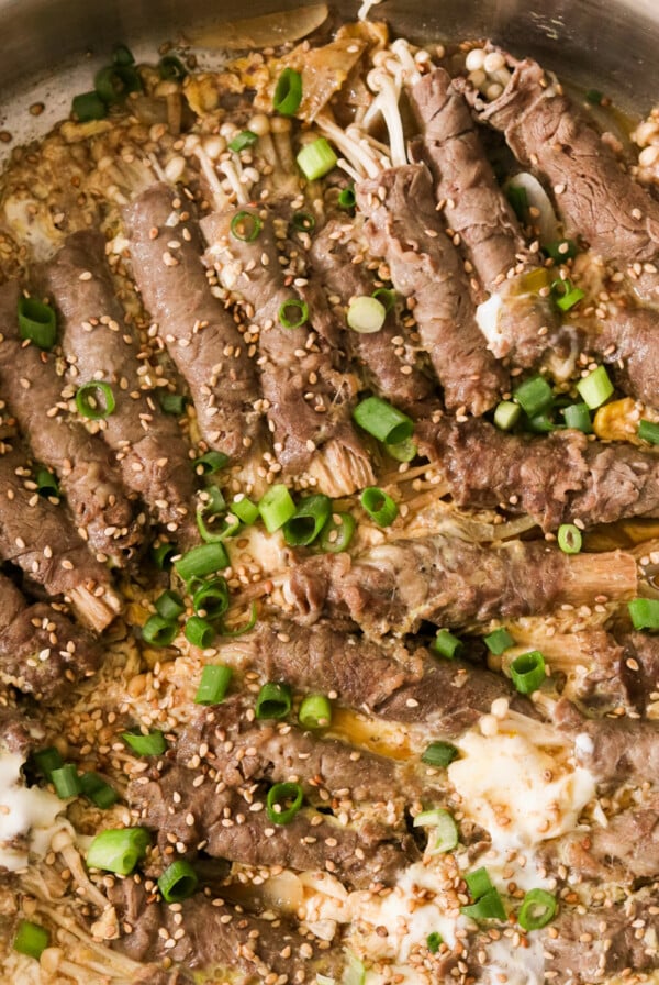 a close up of enoki beef rolls topped with sesame seeds and green onions