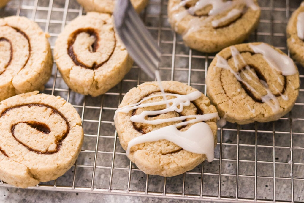 Drizzling icing over gluten free cinnamon roll cookies