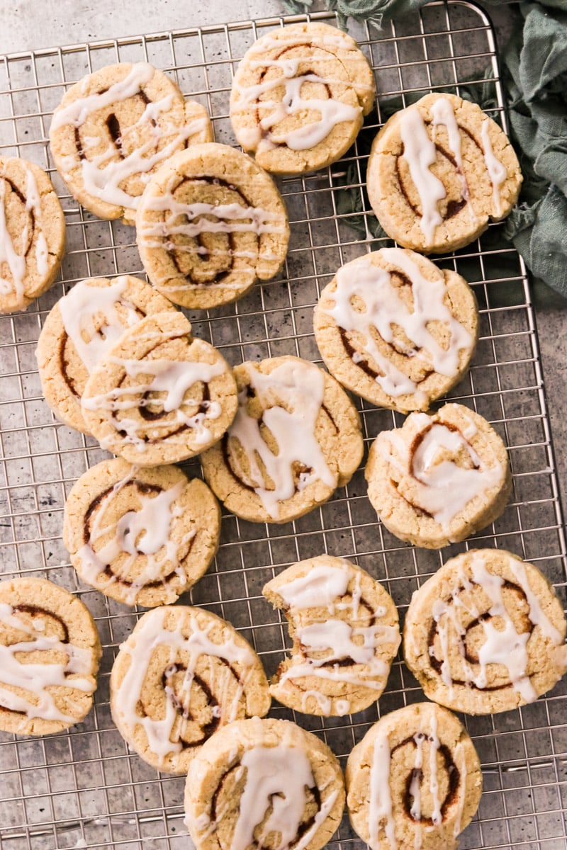 Frosted cinnamon roll cookies resting on a cooling rack.