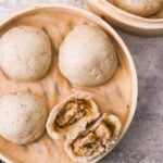steamed pork buns in a bamboo steamer basket