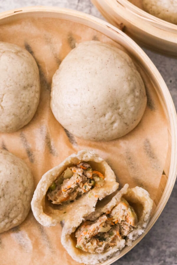 steamed pork buns in a bamboo steamer basket