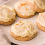 a plate of orange cookies topped with frosting