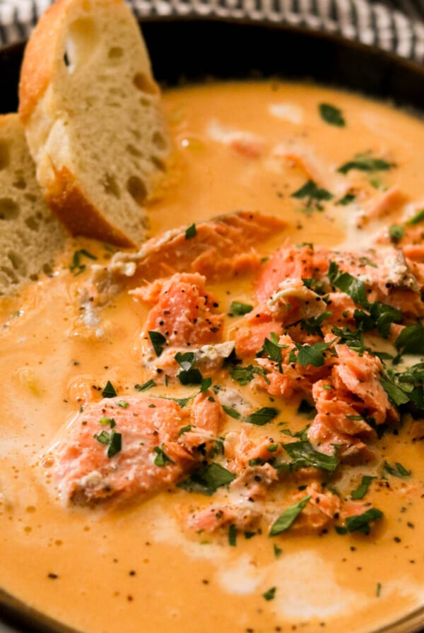 close up of creamy salmon bisque in a dark bowl