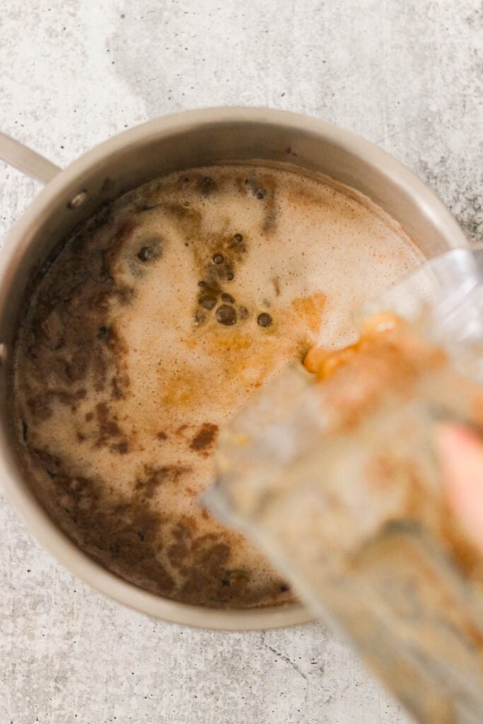 Adding blended seasoning sauce into a pot of beef stew to enhance the depth of flavor.