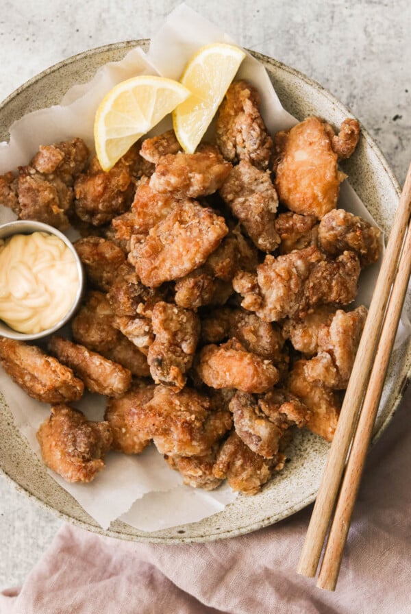 air fryer karaage (fried chicken thighs) on a plate with mayo and lemon wedges