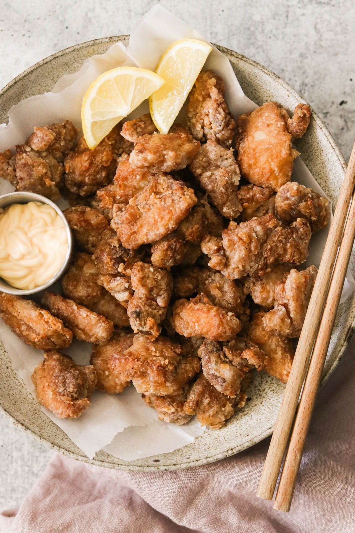 fried chicken thighs on a plate with mayo and lemon wedges 