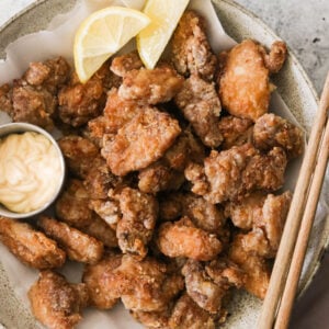 air fryer karaage (fried chicken thighs) on a plate with mayo and lemon wedges