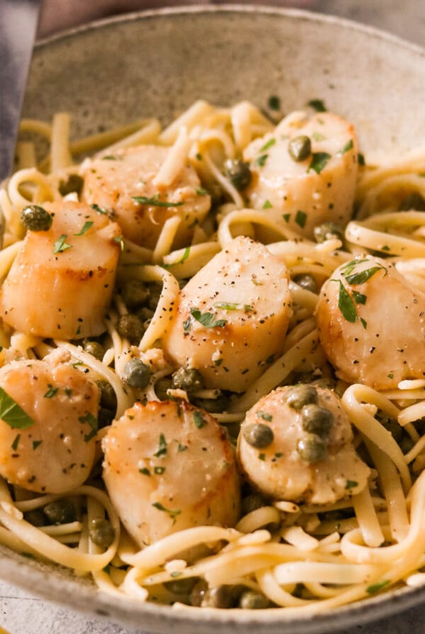 scallop piccata pasta served in a bowl with a fork