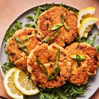 Four crispy tuna patties on a blue plate with herbs