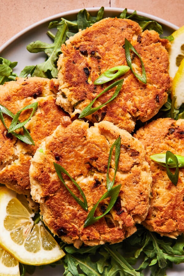 Four crispy tuna patties on a blue plate with herbs