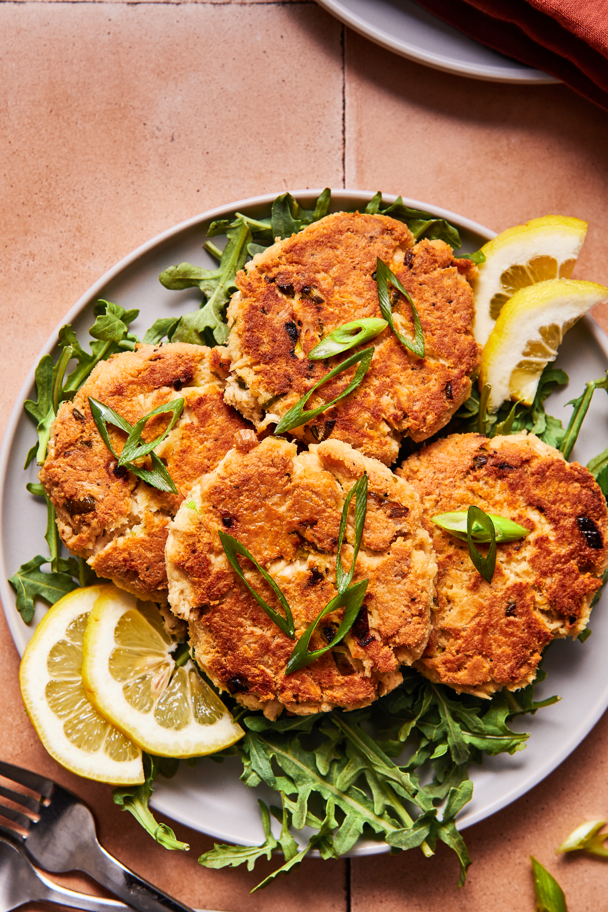 Four crispy tuna patties on a blue plate with herbs