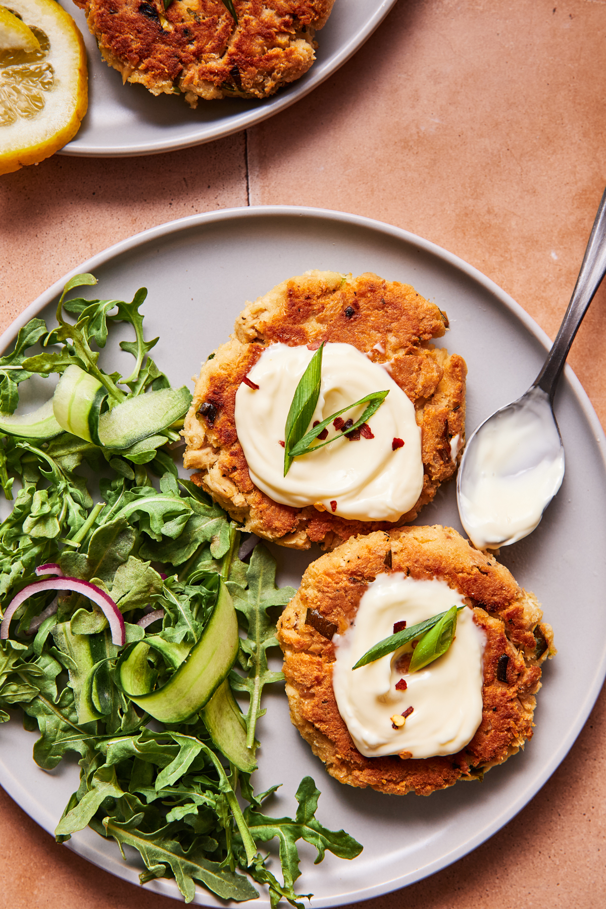 Cooked tuna patty on a salad with mayo, hot sauce, and greens