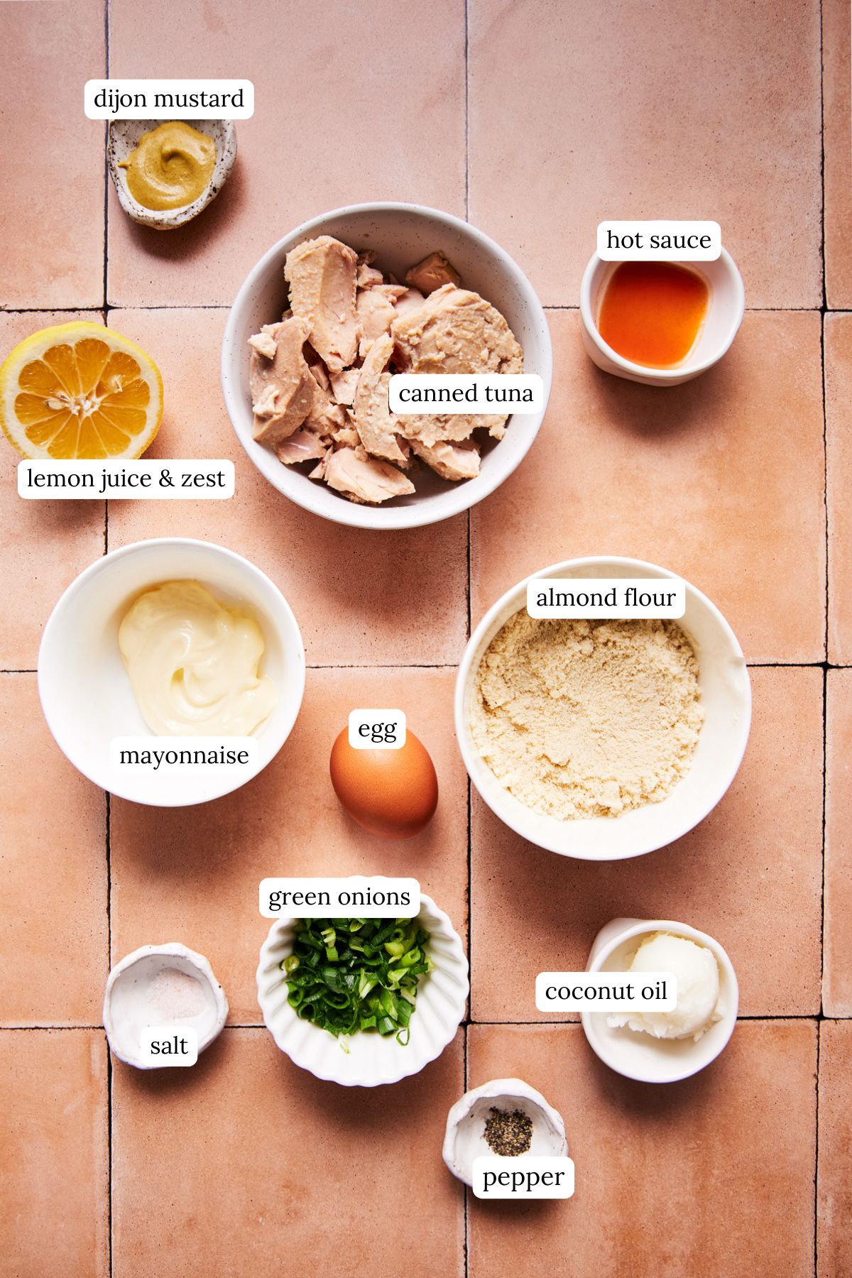 Overhead shot of tuna patty ingredients in small bowls on a white surface