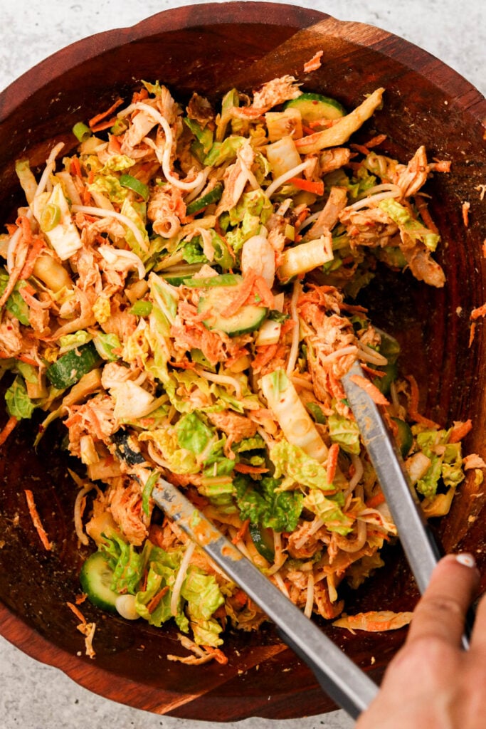 Tossing the salad with bang bang dressing using tongs