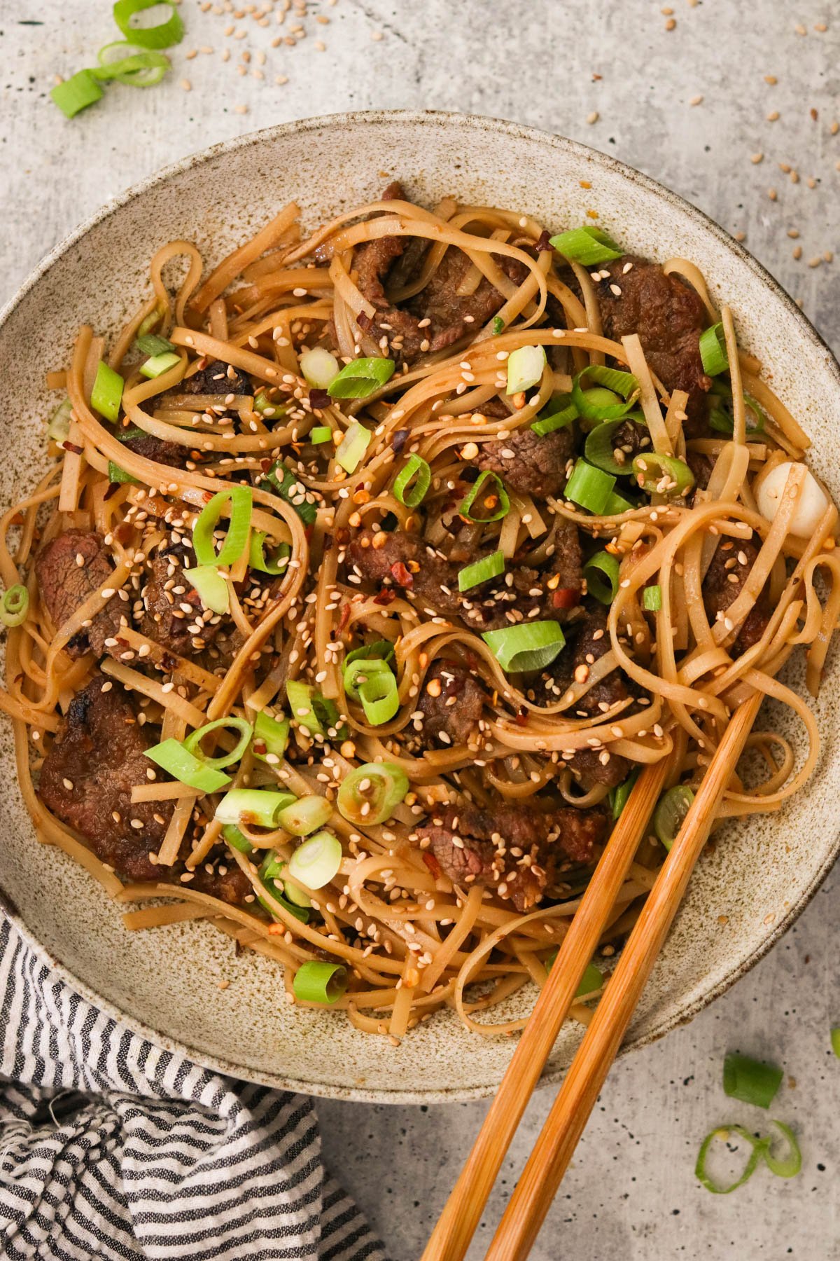 Plated Mongolian beef noodles garnished with red pepper flakes and sesame seeds