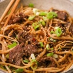 Bowl of Mongolian beef and noodles with green onions and sesame seeds on top