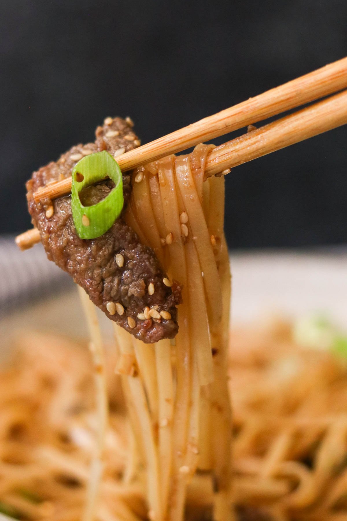 chopsticks holding Mongolian beef noodles