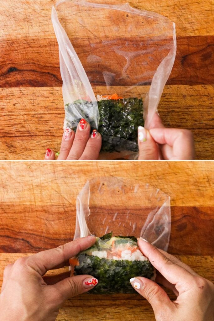 hands folding the bottom edge of rice paper over the sushi filling