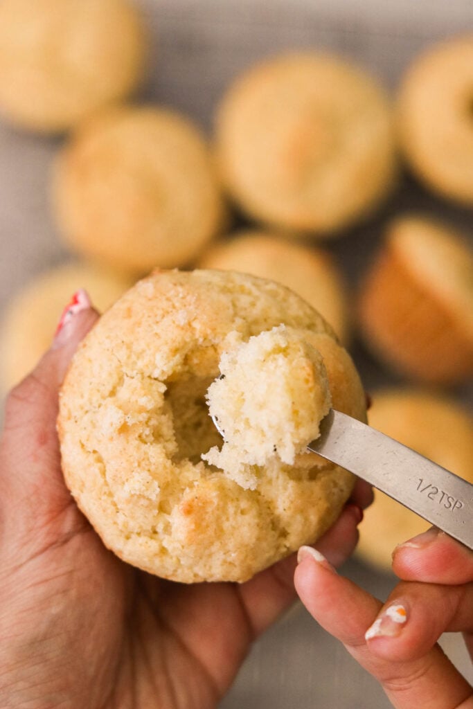 Scooping out the center of a muffin with a spoon to make room for lemon curd

