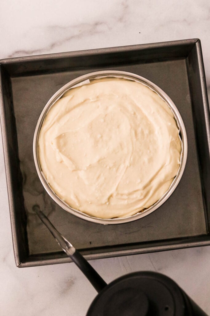an unbaked cheesecake ready to go into the oven with a water bath surrounding the springform pan