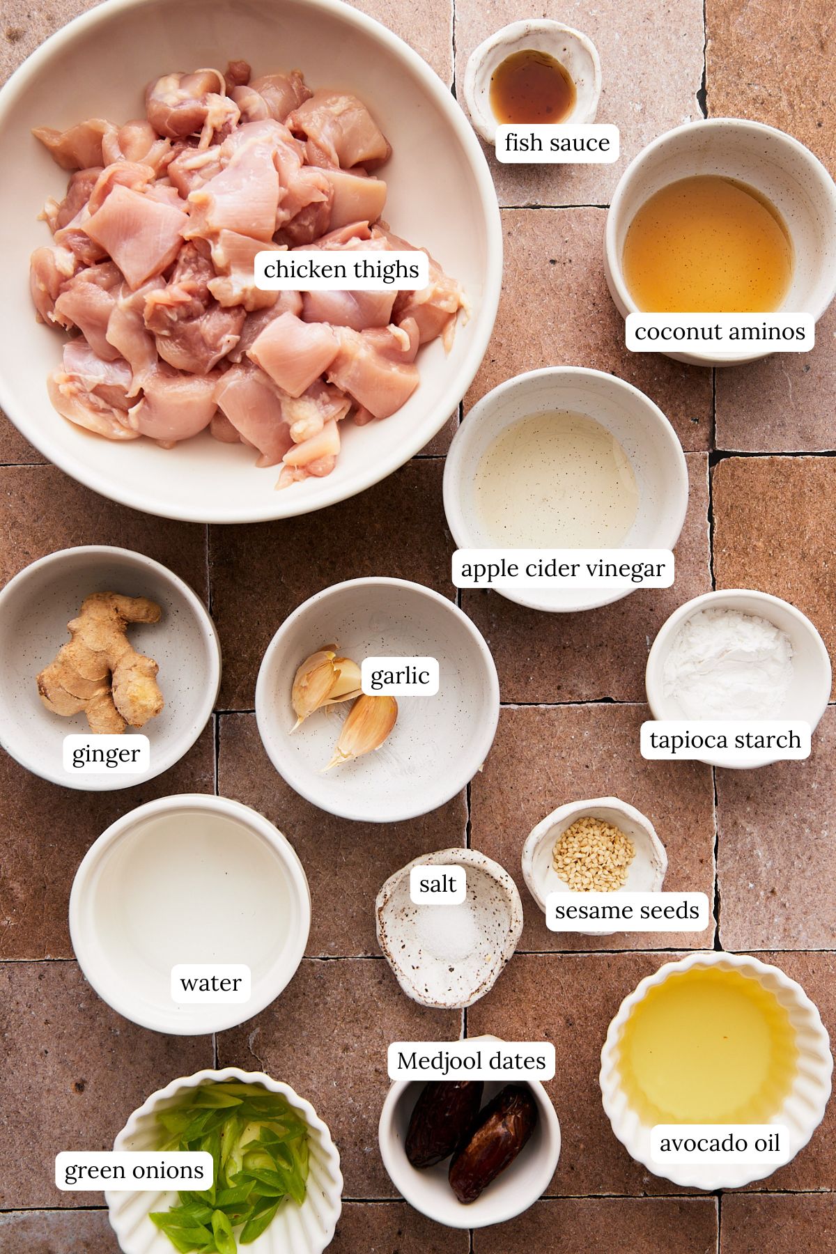 recipe ingredients for sesame chicken in small ramekins and labeled, including diced chicken, seasonings, and oil. 