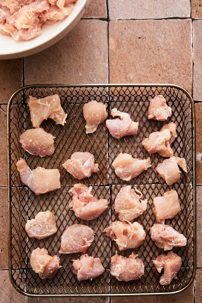 raw chicken arranged on an air fryer tray ready to cook 