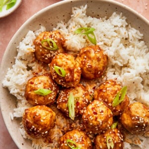 sticky asian chicken meatballs served on a plate with a side of fluffy white rice