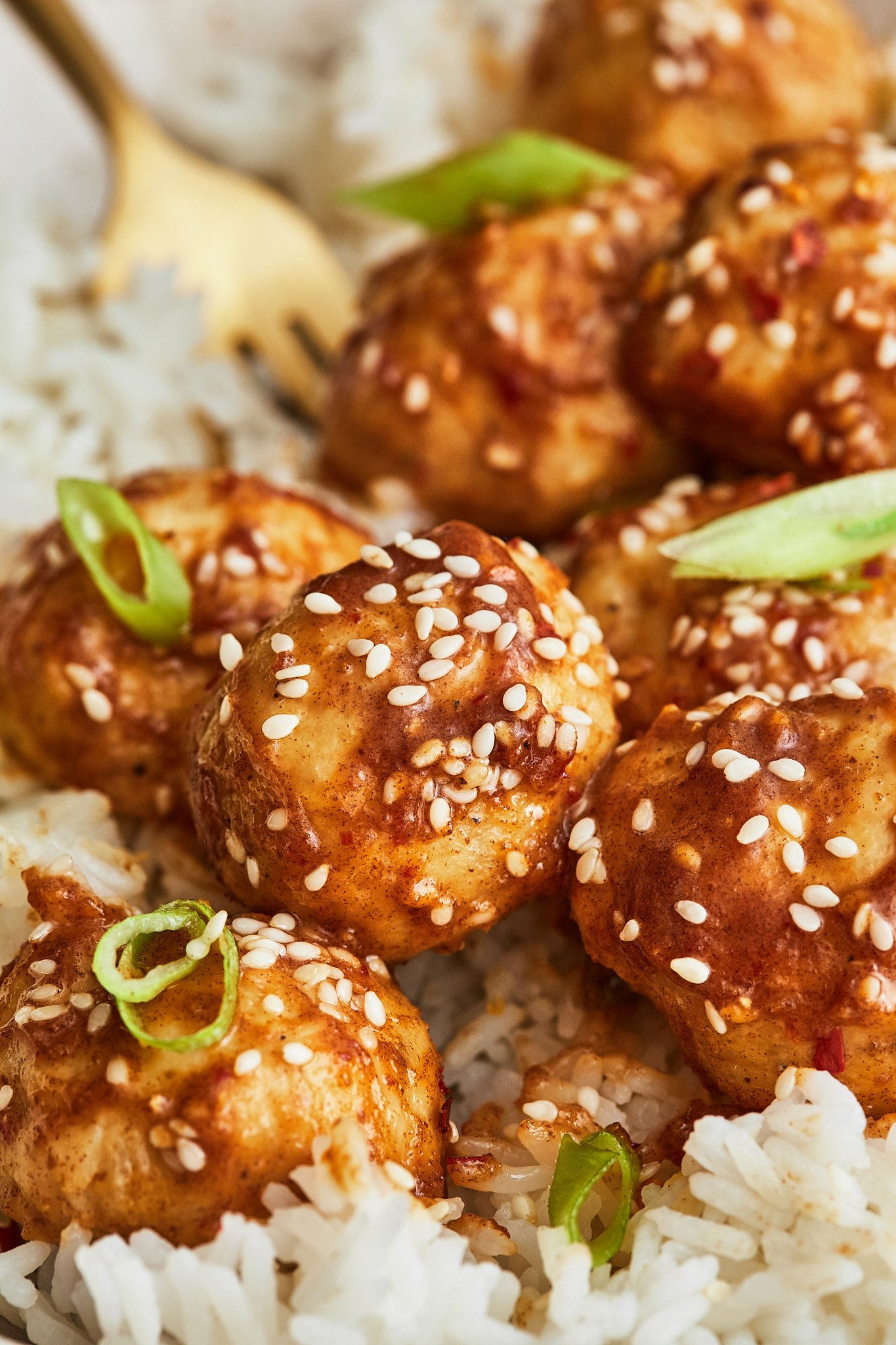 a close up shot showing perfectly round and juicy meatballs covered in a sticky asian sauce