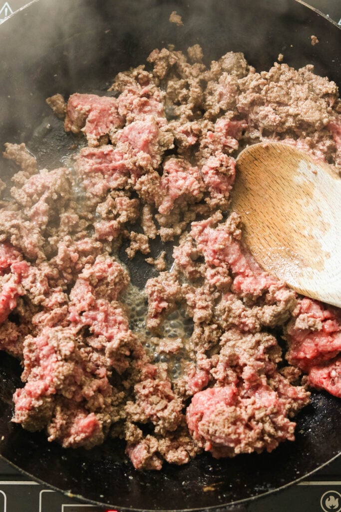Skillet on the stove with ground beef browning, ready for taco seasoning and lime juice